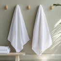White long towels hanging on wall hooks in a modern bathroom