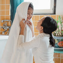 Mum wrapping child in a soft white towel