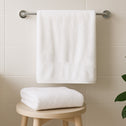 White towel on rail and folded on stool in bathroom