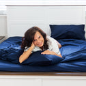 A lady laid on top of a soft bed smiling.