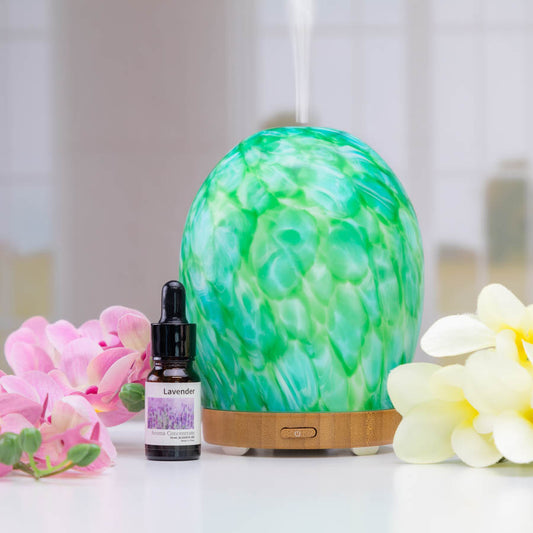 Round, Green diffuser with a Lavender essential oil placed next to each other.