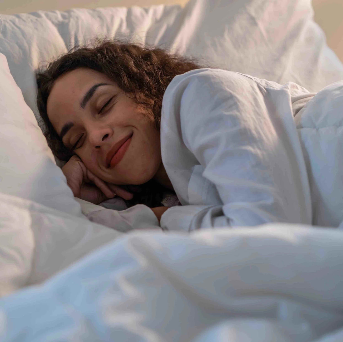 Young woman lying down on bed with comfortable smile on her face.