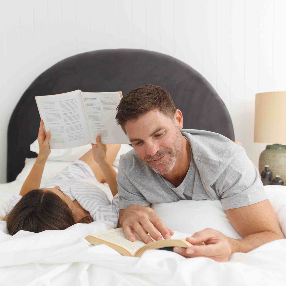 Middle aged man and woman reading a book while on their comfortable bed mattress.