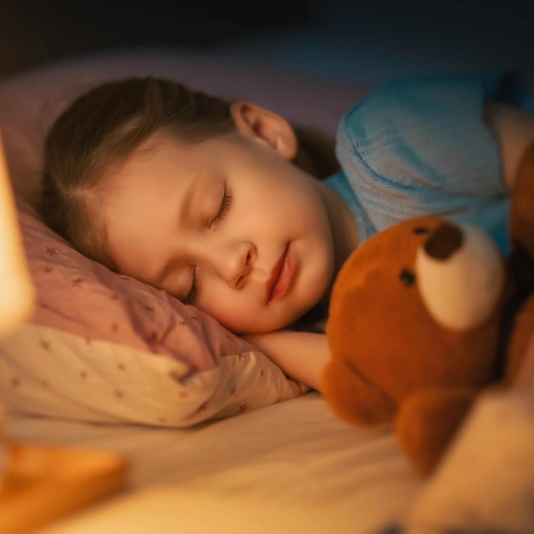 Young child soundly asleep while cuddling with toy bear.