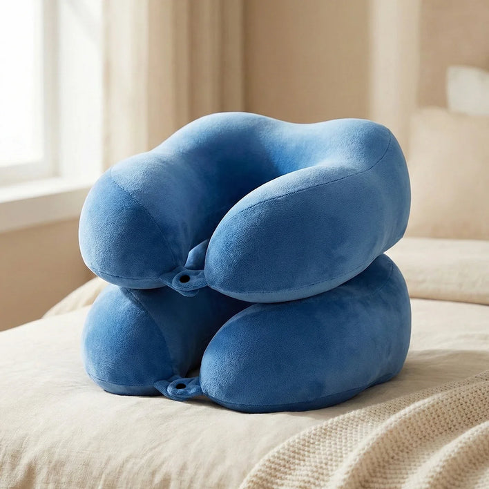 Blue memory foam travel neck pillow on bed with soft plush cover