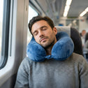 Man sleeping comfortably on train with supportive memory foam neck pillow
