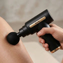 Handheld mini massage gun providing targeted leg muscle therapy