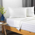 Double pillows upright on neat bed with soft sheets