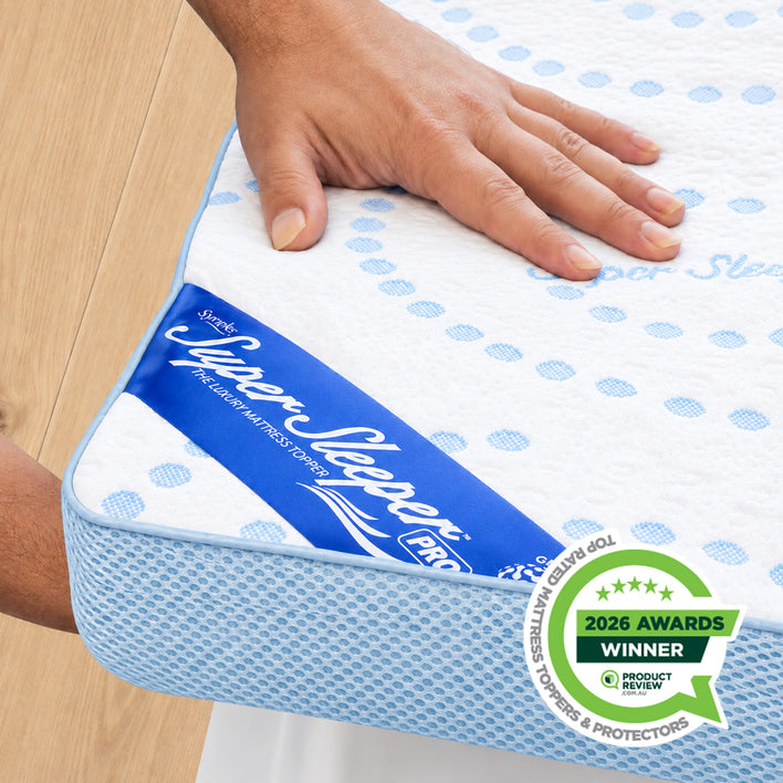 A hand presses down on the Straight 2 Sleep® Mattress Topper by Super Sleeper Pro, with the Super Sleeper Pro label visible. A 2026 Awards Winner badge from Product Review is displayed in the lower right corner. The topper showcases a white and blue polka dot design.