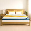A bright, minimal bedroom featuring a neatly made bed with a light wood frame, yellow accents, and the Super Sleeper Pro [Super King] Straight 2 Sleep® Mattress Topper with Cooling Technology + FREE Pillows. A lamp and plant sit on the nightstand.
