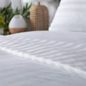 An up-close view of bedding adorned with stripes, accompanied by a diffuser