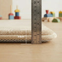 A metal ruler stands next to the Super Sleeper Pro Plush Soft Touch Sensory Tatami Mat, showing its 3.5 cm thickness. Beige mat looks like a rug, but works as a play mat; blurred wooden toys and light wood floor in the background.