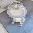 The Super Sleeper Pro Plush Soft Touch Sensory Tatami Mat, designed to look like a rug but work as a play mat, features gray and white colors with plush toys and a padded roller, placed on light-colored carpet in the living room.