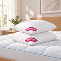 Two white Marshmellow plush pillows stacked on a quilted mattress in a bright bedroom setting.