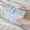 Two hands hold a folded Royal Deluxe Imperial Dream Sheets™ Cotton Sateen 1200TC 4pc Set by Super Sleeper Pro, labeled as Buy 1 Get 1 FREE, shown with matching organizer bands for elegant comfort in your bedroom.