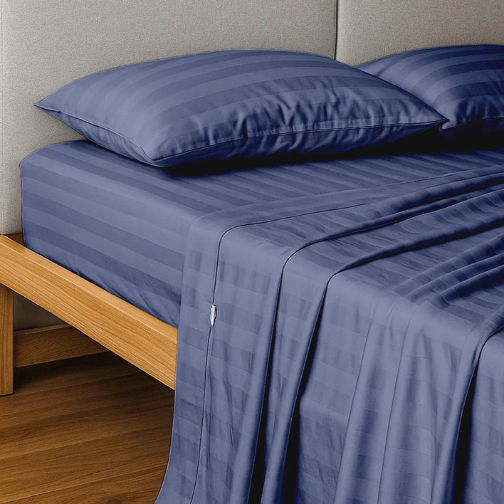 A neatly made bed with a light wood frame features Super Sleeper Pro's Buy 1 Get 1 FREE: Royal Deluxe Imperial Dream Sheets™ Cotton Sateen 1200TC 4pc Bedding Set. A padded light gray headboard and wood flooring complete the look.
