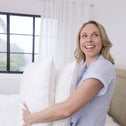 Woman holding multiple Marshmellow hotel pillows to show lightweight feel and plush support