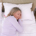 Side sleeper resting on plush white hotel pillow with full neck and shoulder support