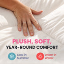 A close-up of a person's hand resting on soft white bedding, with text reading 'PLUSH, SOFT, YEAR-ROUND COMFORT' and icons noting 'Cool in Summer' and 'Warm in Winter'.