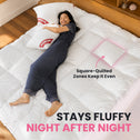 A woman lies on a white quilted bedspread or mattress topper in a bedroom setting, with text reading 'Square-Quilted Zones Keep It Even' and 'STAYS FLUFFY NIGHT AFTER NIGHT.' The product being shown is the white quilted bedding surface rather than the person or room decor.