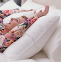 Woman lying on a white inflatable bed with floral pajamas.