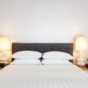 Hotel style bedding laid freshly in-between golden lamps