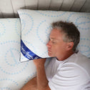 A middle aged grey haired man sleeping peacefully on a fluffy pillow embellished with blue swirls