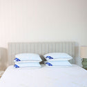 Four pillows arranged neatly atop a bed, which features a headboard in a subdued shade of gray.