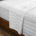 Luxury white bed linen draping over a dark wooden bed.