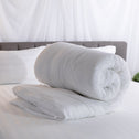 A super soft quilt cover rolled neatly on a well-presented bed.