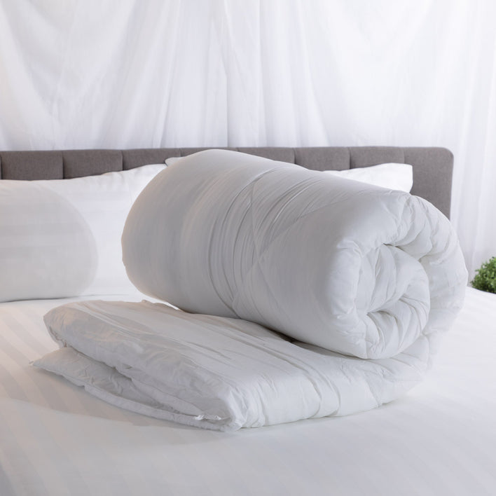A super soft quilt cover rolled neatly on a well-presented bed.