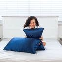 A lady sat in bed with two silk navy pillows