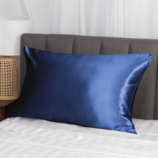 Sleek, silk navy pillow on a modern bed.