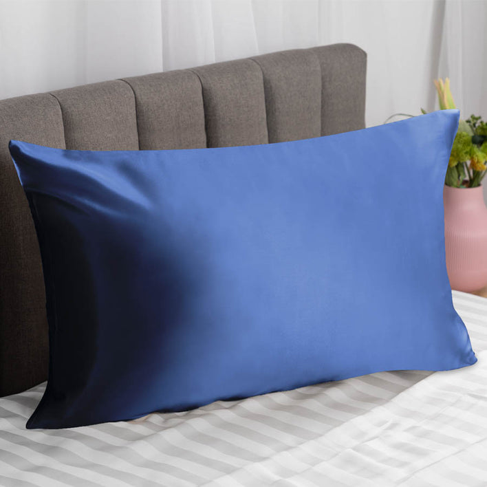 . A navy silk pillowcase neatly placed on a modern bed