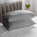 Two soft pillows neatly stacked on top of each other in a grey colour.