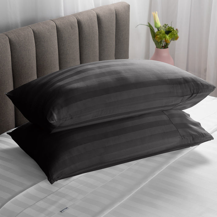 Two soft pillows neatly stacked on top of each other in a black colour.